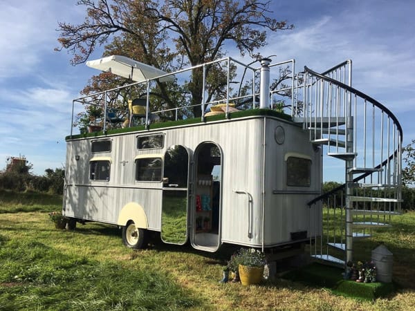 vintage glamping trailer with silver trim and deck on top