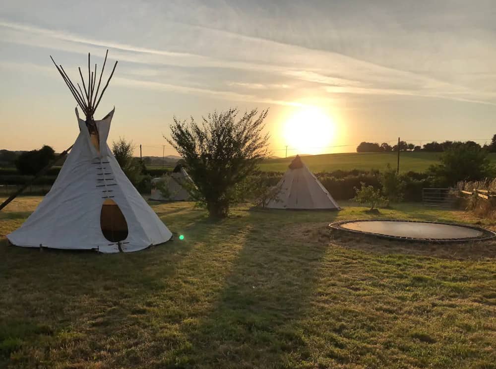 glamping tipis with sunset in the background
