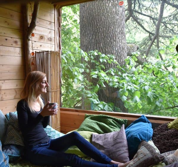 woman looking out of the window of Au Fil de Soi Treehouse