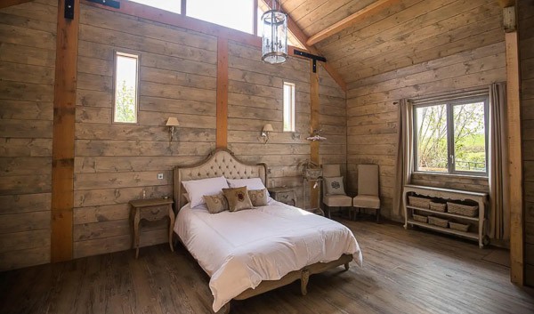 Glamping cabin inside view with bed, high ceiling and window