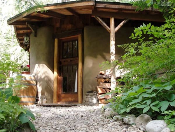 Cedar Fern Cob Cottage Glamping spot view of the front door with a barrel and wood