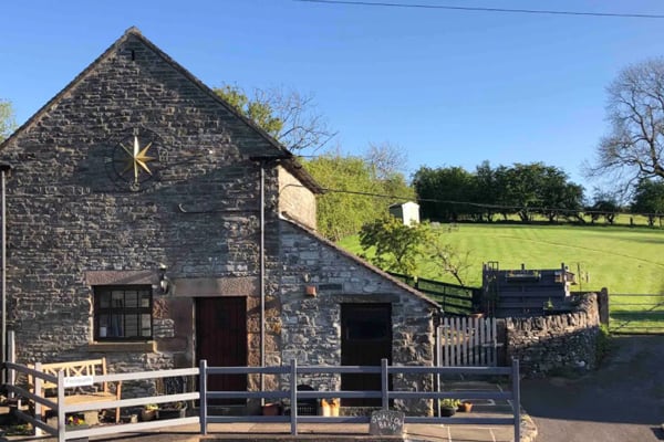 glamping barn made of stone with a fence in front