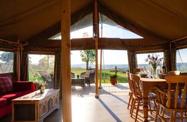 safari glamping tent in New Forest. View of the inside looking out the door with couch, table and chairs.