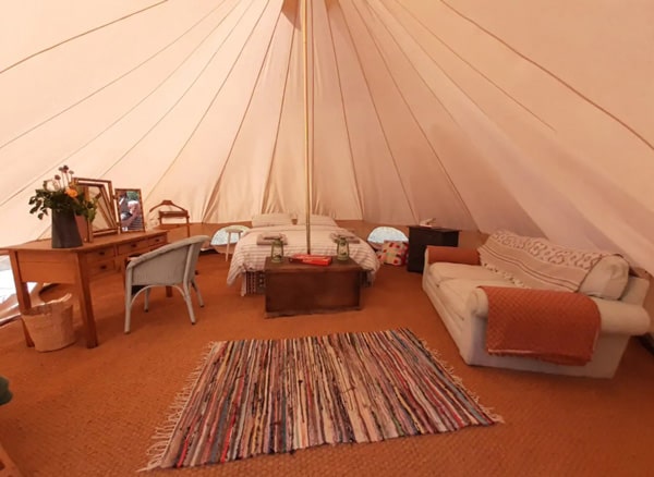 Tent Glamping Essex in a Private Nature Reserve view of the inside of the tent with bed, desk and couch