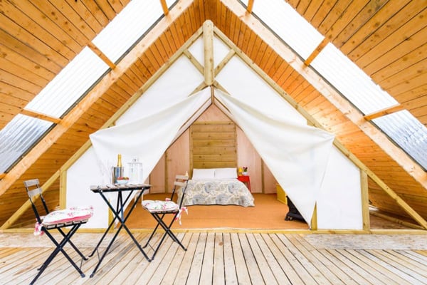 Tent Glamping in Killarney at The Grove view of the tent deck with table and chairs and bed inside
