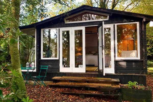 Romantic Glamping Fermanah Hut with Lake, view of the front with bed and stairs and trees around