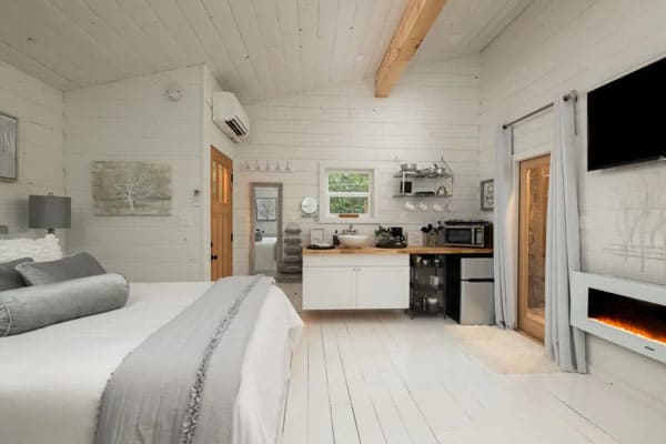 Romantic Asheville Treehouse with Hot Tub view from inside with bed and kitchenette and tv on all. Walls are white