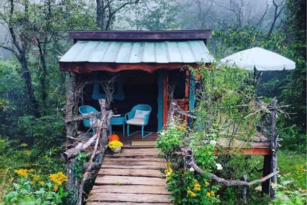 Fairytale Asheville Treehouse Cottage view of treehouse from front with chairs and bridge