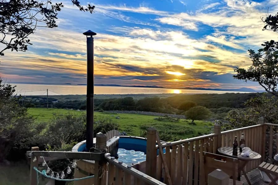 Shepherds Hut Glamping With Hot Tub North Wales view from the deck with hot tub and the sea in the distance at sunset