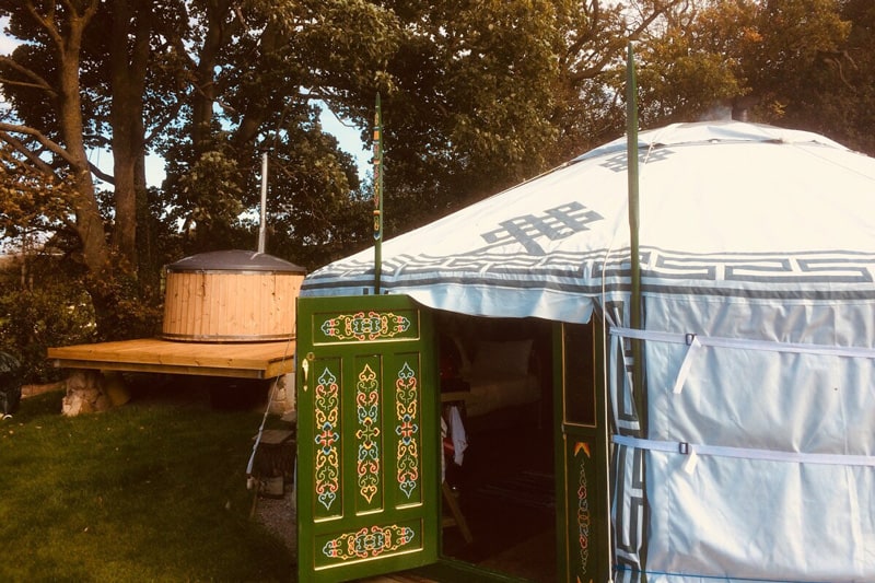 Crazy Pheasant North Wales Yurt view of outside of yurt with door open and hot tub in the back