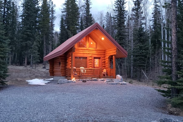 Little Nordegg Brazeau Glamping Cabin view of the front of cabin with outdoor porch light on in the woods