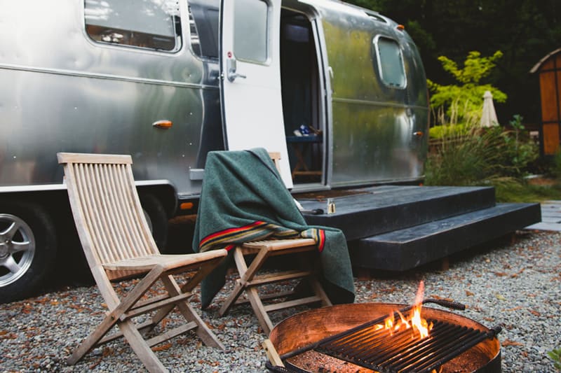 glamping airstream bay area autocamp view of the firepit, to wooden chairs and the side of the airstream