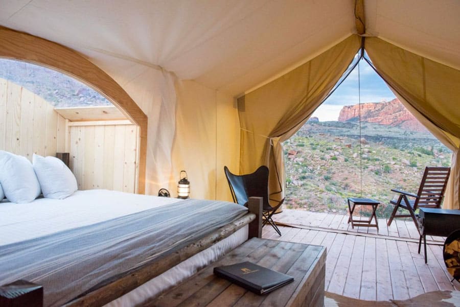 Under Canvas Zion tent view from inside with door open, bed with viewing window above it and chairs on porch