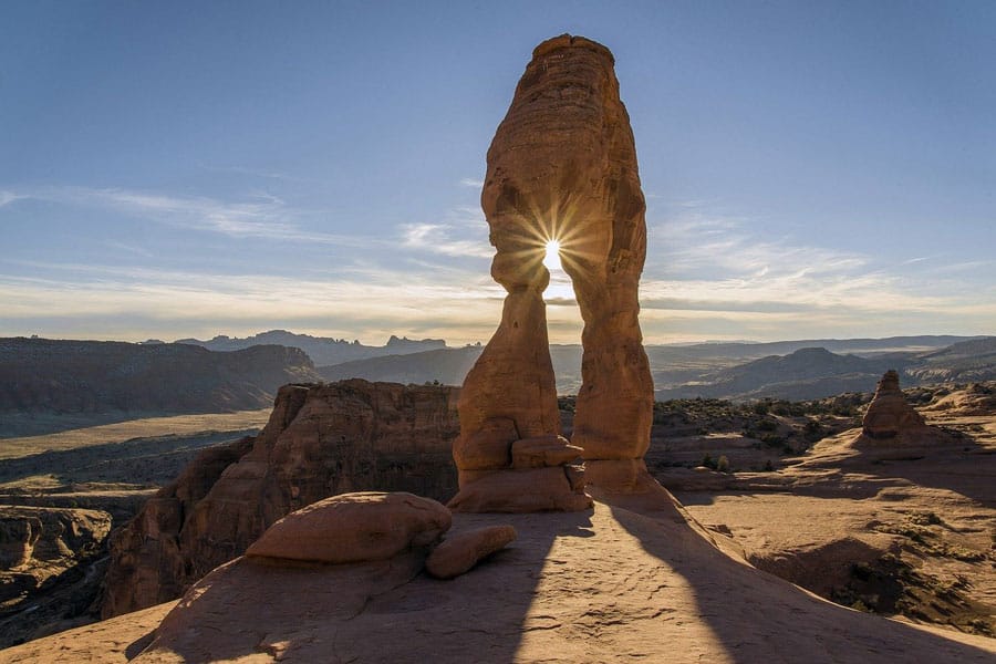 view of arch rock formation with sun peaking through