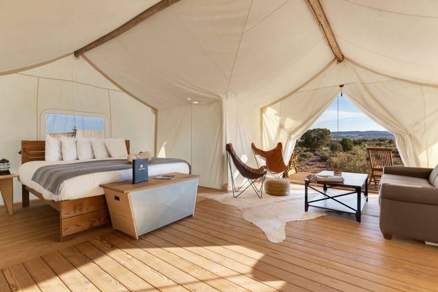 undercanvas moab glamping tent view from inside with bed, chairs, couch and door open to a view